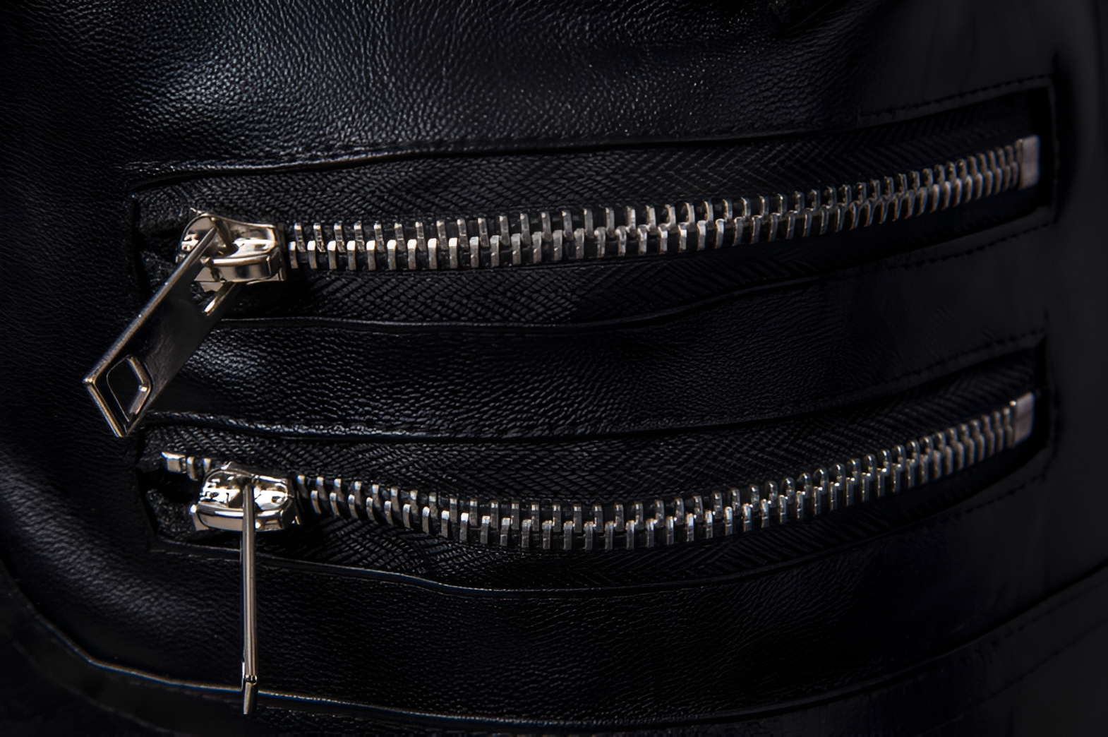 Detalle de cierres metálicos múltiples en chaleco rockero cruzado estilo biker