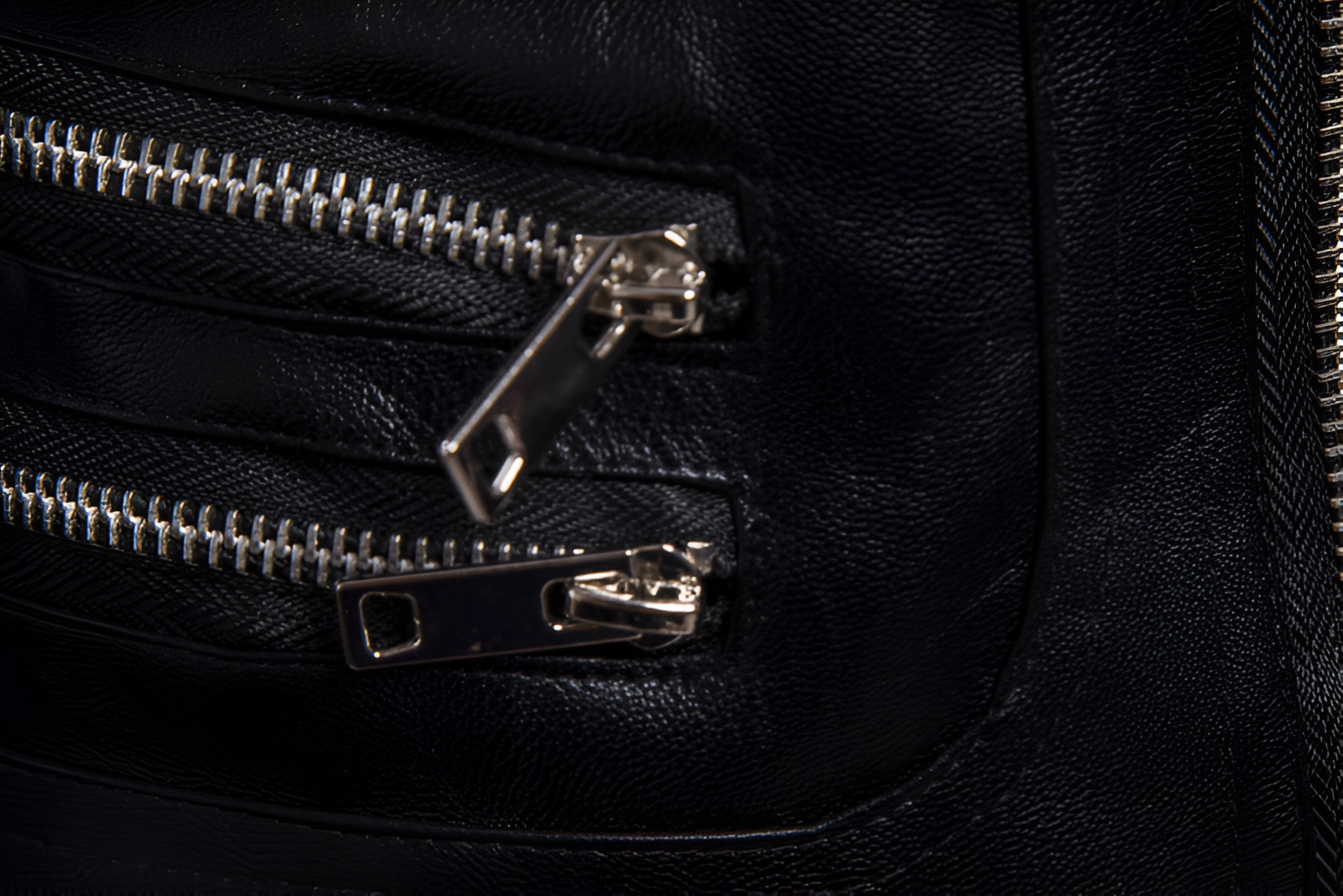 Primer plano de cierres industriales en chamarra de piel rockera para hombre